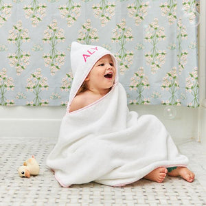 child in a weezie hooded towel sitting on the bathroom floor